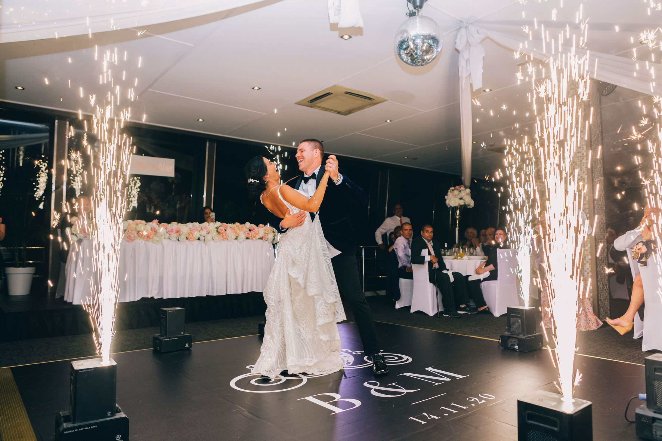 First dance under cold sparks, the couple’s monogram projected on the floor